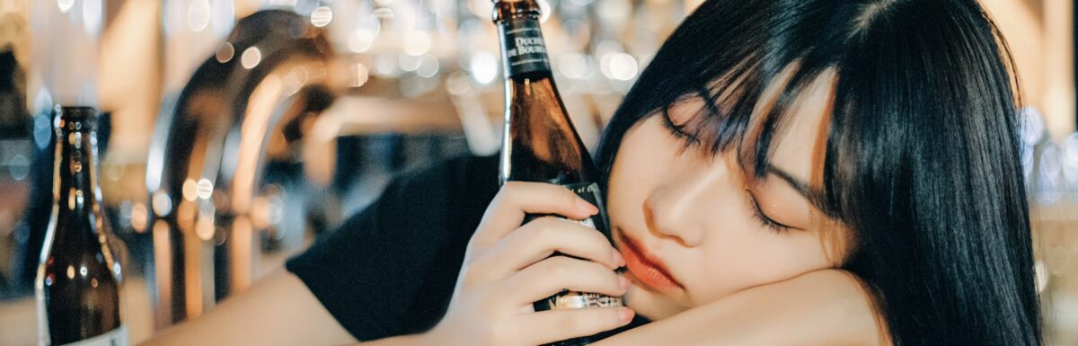 Girl with a bottle of beer asleep in the pub