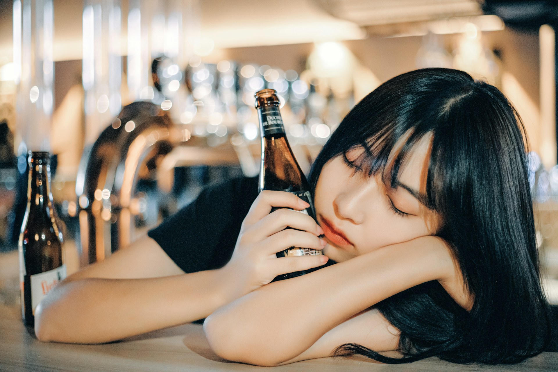 Girl with a bottle of beer asleep in the pub